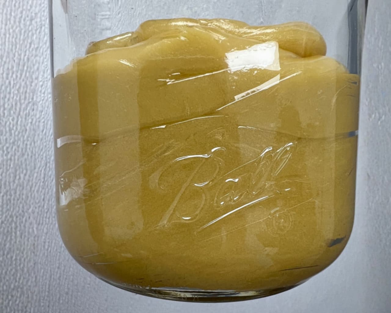A glass jar packed with freshly pressed live rosin, curing