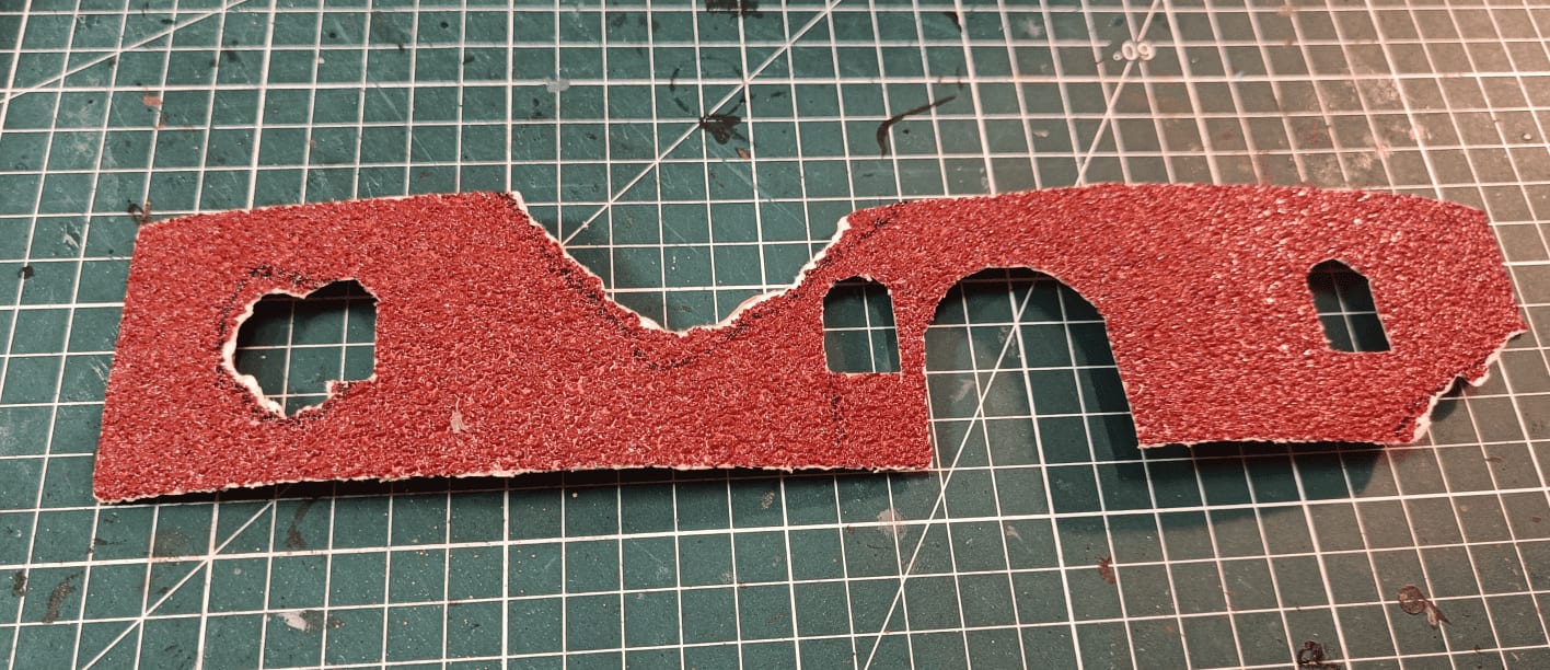 Cut sandpaper with holes for windows and doors