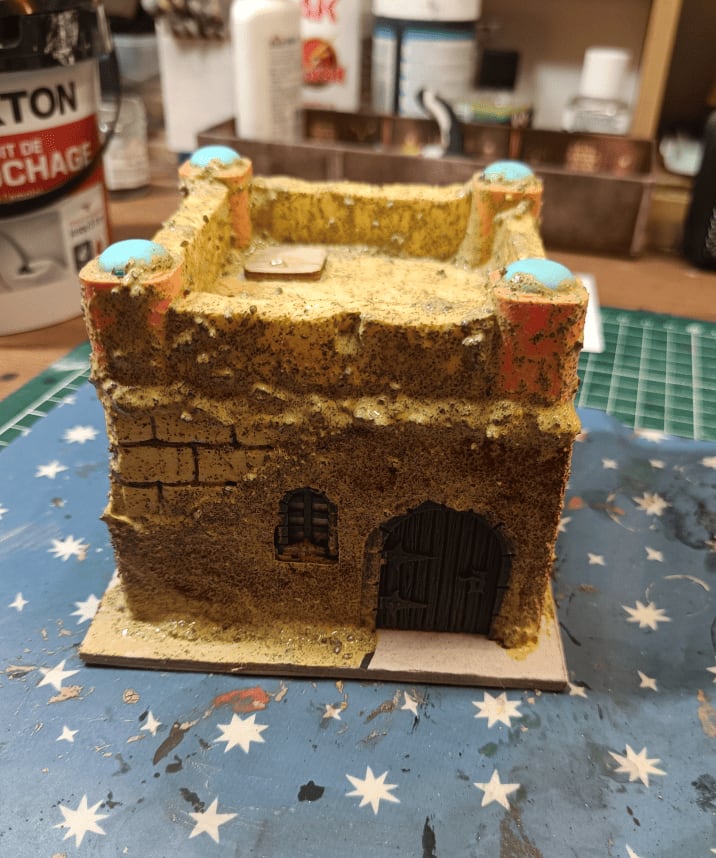 House covered in sand and glue texture with raised trapdoor on roof
