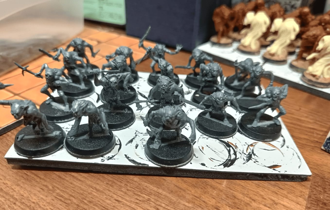 Assembly line of unpainted Moria goblin miniatures showing different sculpts