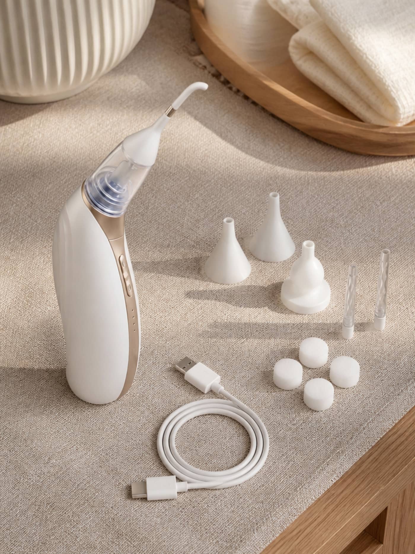 Vacurio complete bundle flat-lay on warm wood surface — device, silicone tip set, and charging cable arranged generously with natural window-quality light