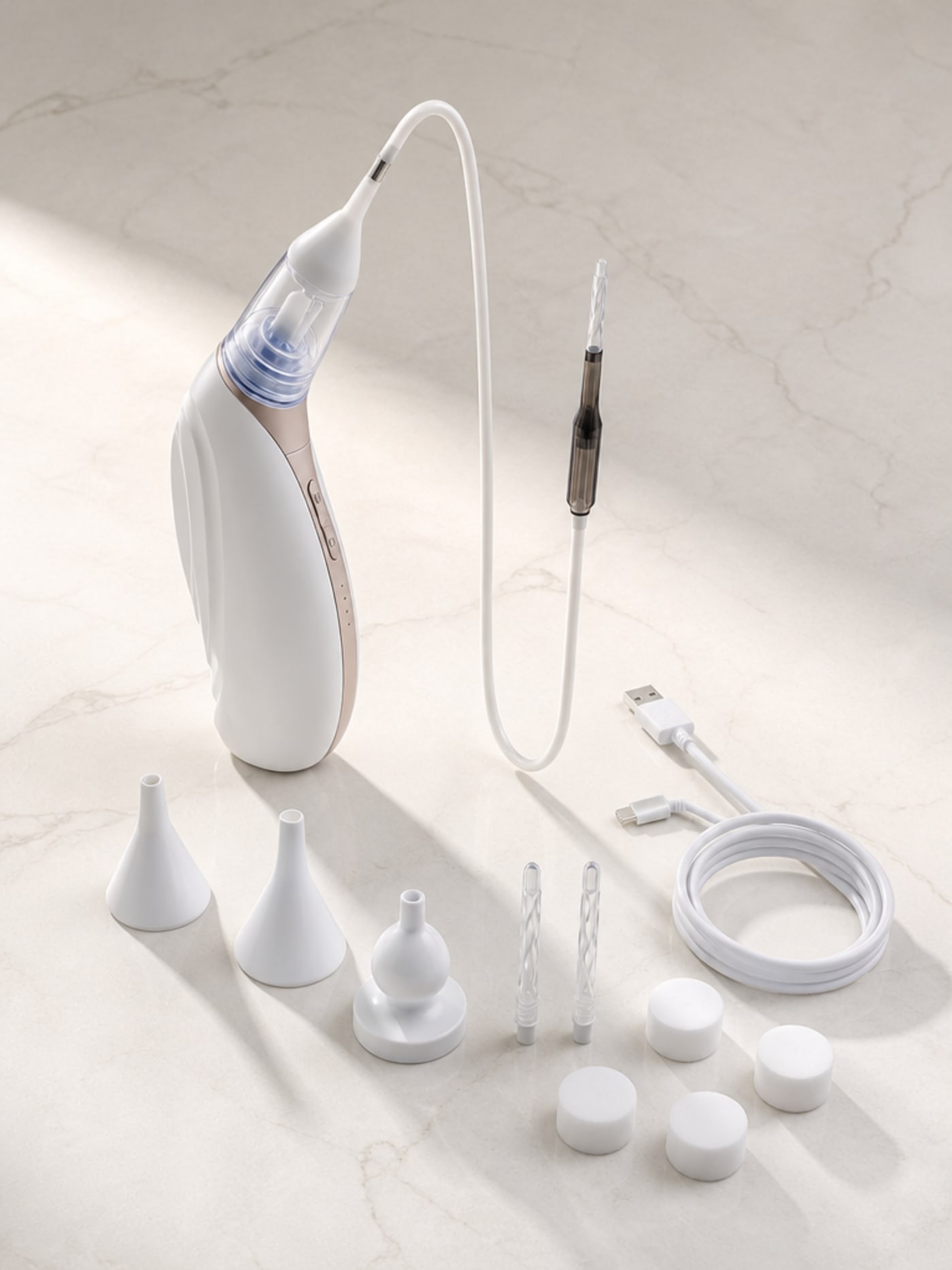 Vacurio cordless ear-cleaning device alongside the complete set of soft silicone replacement tips, arranged on a clean pale stone surface