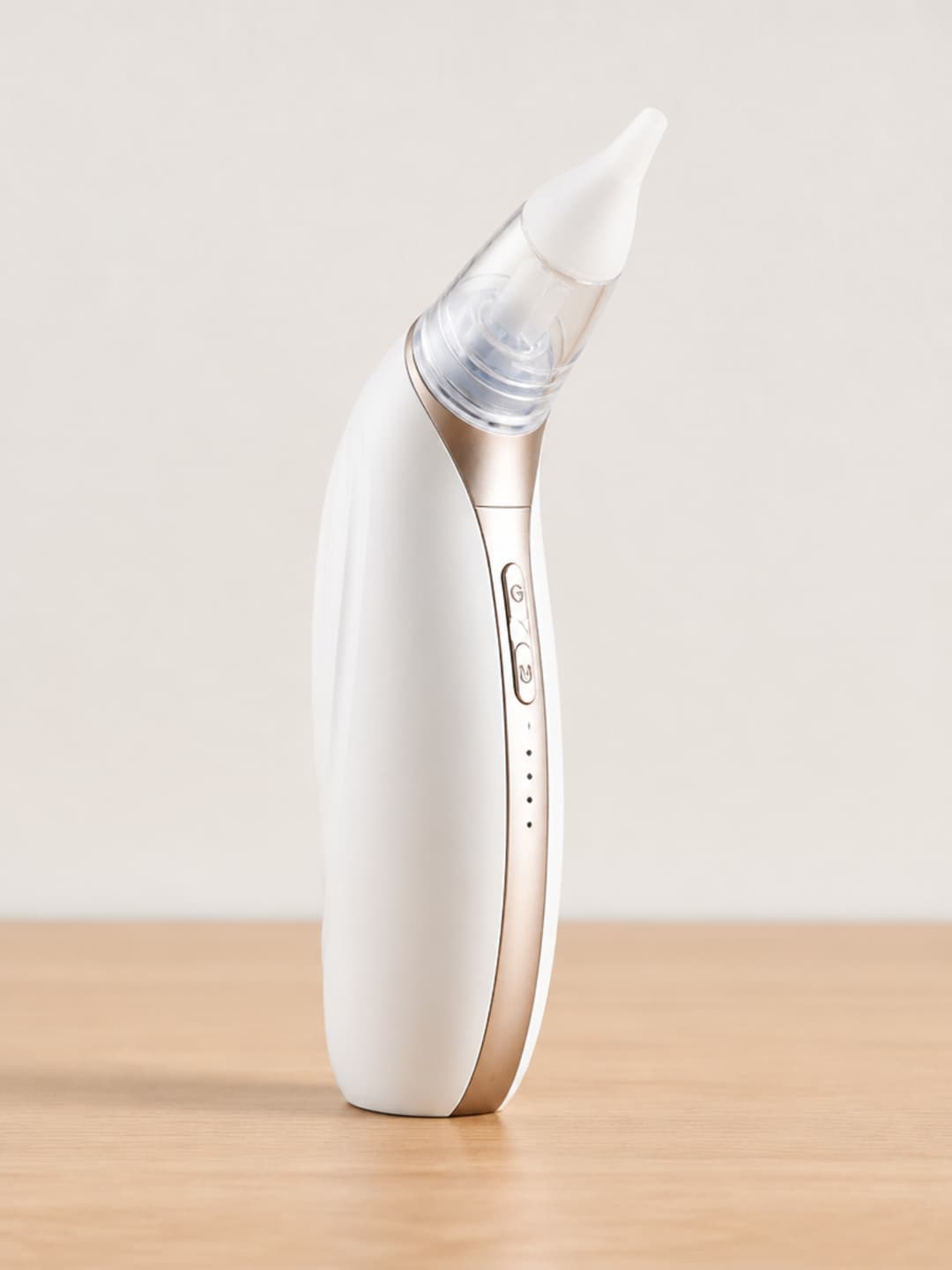 Vacurio ear suction device shown upright on a light-oak surface, transparent collection chamber and soft silicone tip clearly visible.