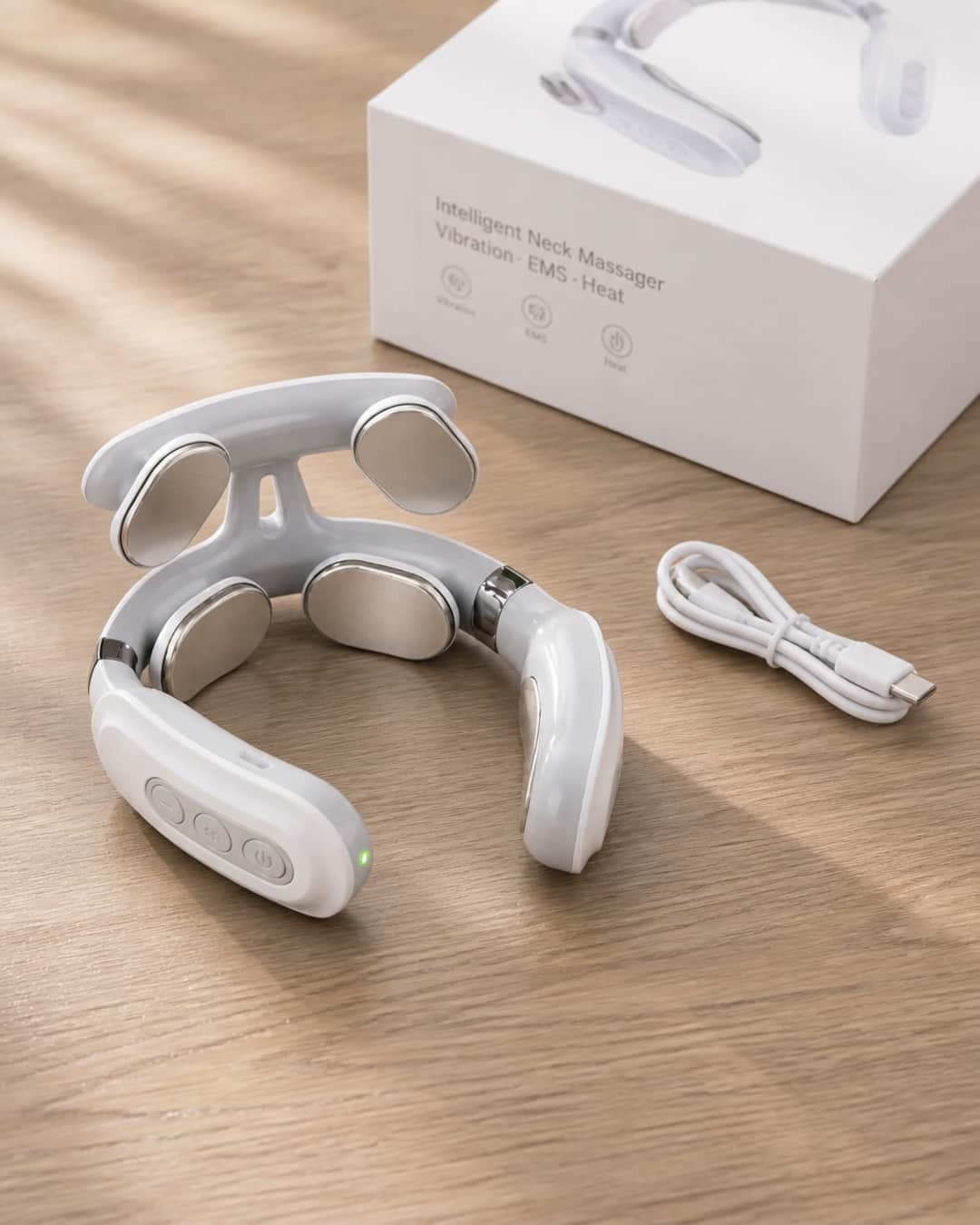 Avenora KnotEase wearable neck device displayed on a warm natural wood surface — the horseshoe-shaped device angled to show both the outer shell and inner electrode contact surface, with product packaging alongside.