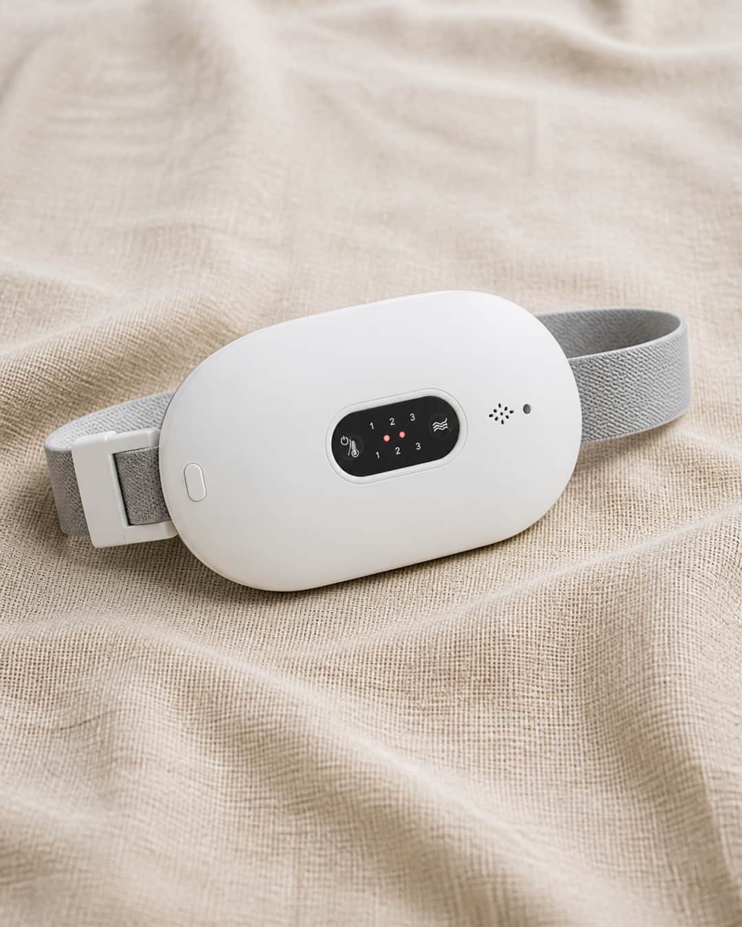 DayDefender wearable menstrual comfort belt laid flat on a natural linen surface, softly lit, showing the product's textile construction and flexible form. Clean, editorial product photograph.