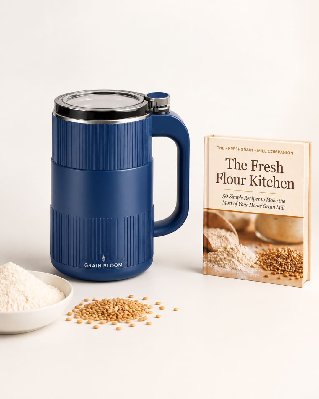 GRAIN BLOOM mill with companion book, whole grain berries, and a bowl of flour