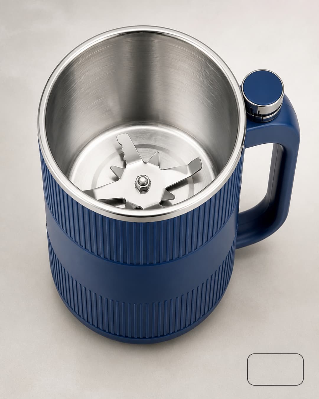 Overhead view of GRAIN BLOOM mill with lid off, showing the metal milling cup and star-shaped blade