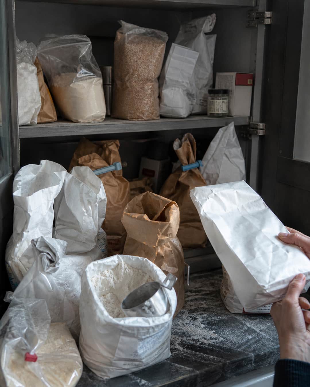 Cluttered American kitchen pantry packed with half-used specialty flour bags and leftover baking experiments