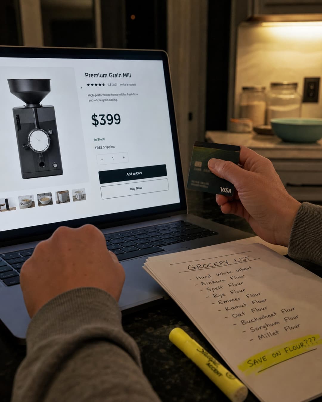 Home baker at a laptop looking at a roughly $400 premium grain mill listing while holding a credit card and a grocery list of specialty flours