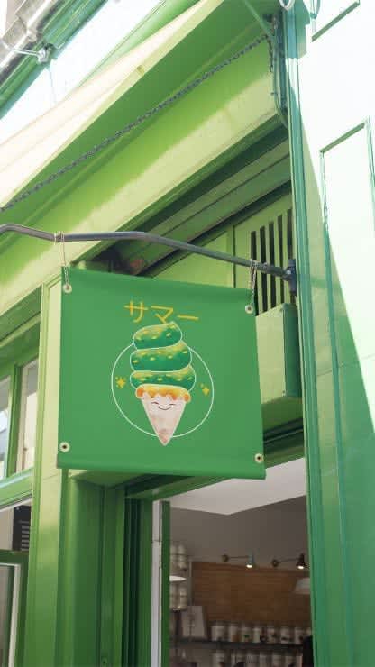 A squared store sign featuring a kawaii green colored ice cream cone, placed on a light green building