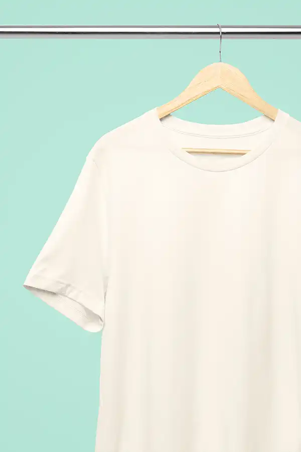 Professional Bella Canvas 3001 Natural T-Shirt Mockup Hanging on a Steel Bar With a Soft Papaya Mint Background