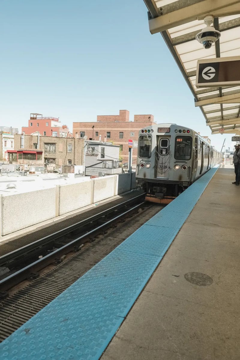 CTA 'L' train pulling into an elevated station platform in Chicago on a sunny day