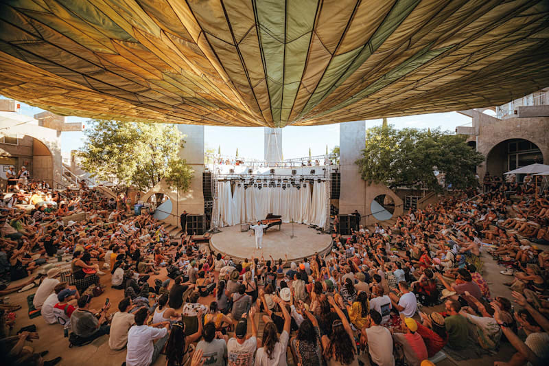 Crowd gathered beneath a canopy at FORM Arcosanti