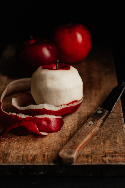 Apple sitting on cutting board with peel cut in a spiral