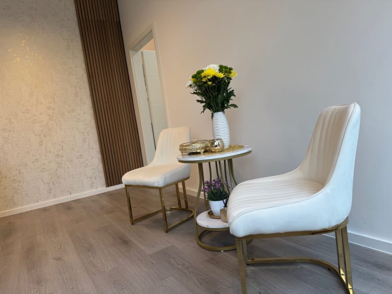 Sitzecke mit goldenen Stühlen und frischen Blumen im Studio