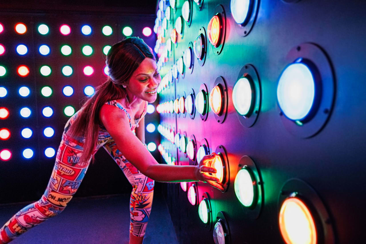 A player presses glowing circular targets on a wall of coloured LEDs.