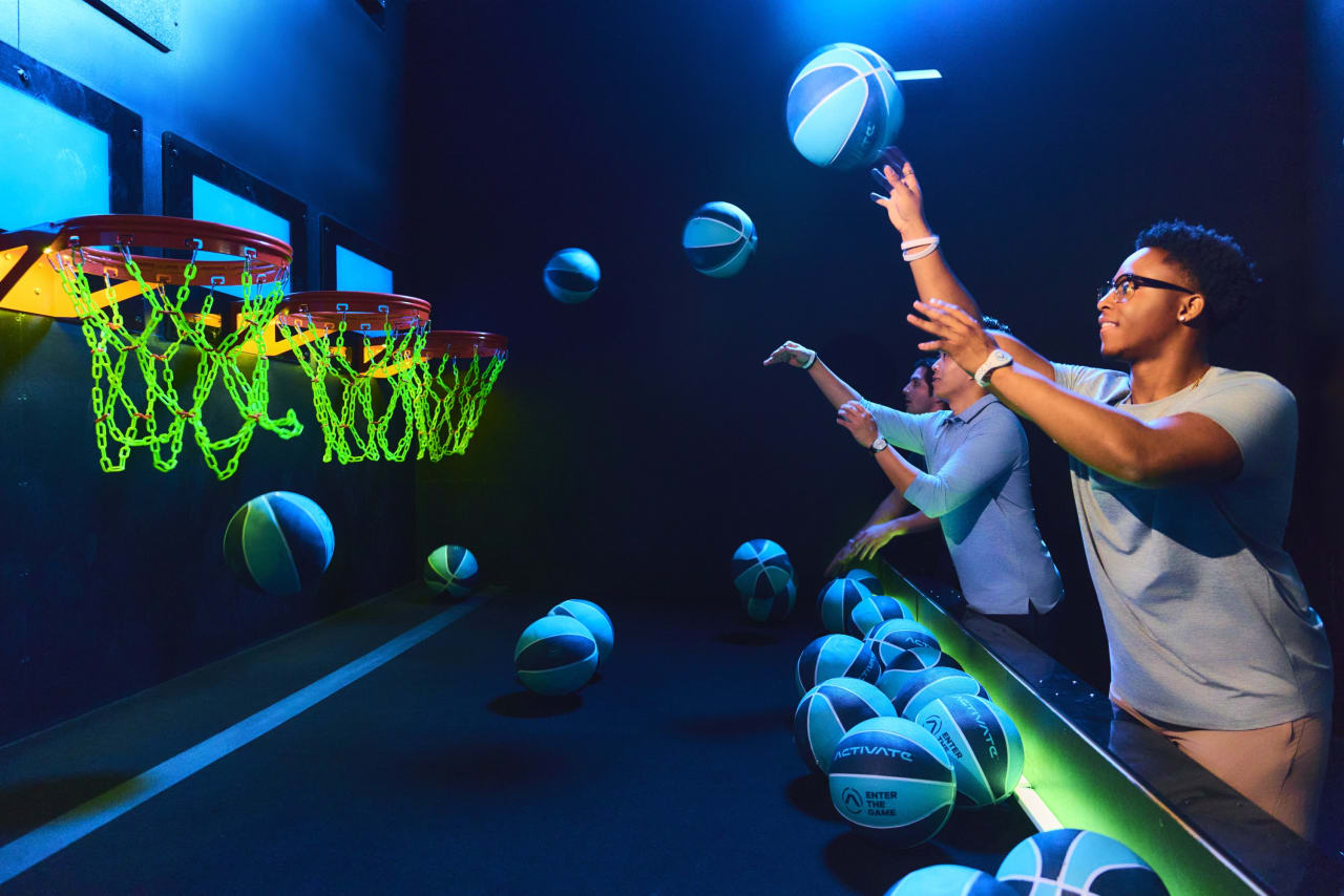 A player launches a glowing basketball toward the hoops in the Hoops room.