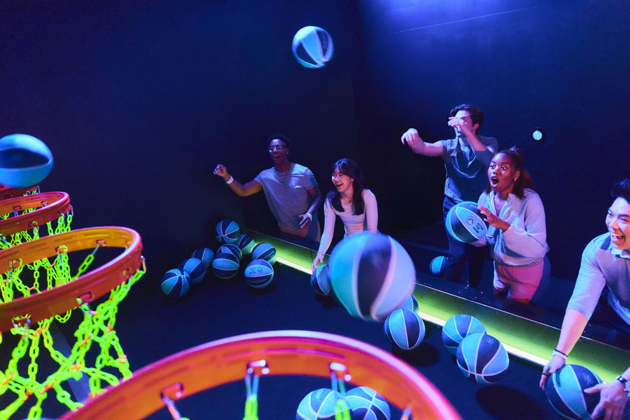 Players compete to shoot glowing basketballs into the lit hoops.