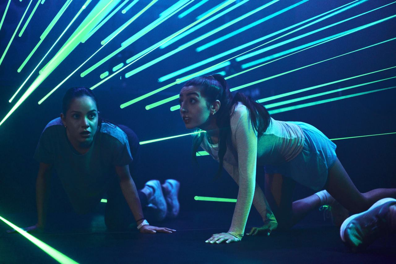 Two players crawl beneath a field of blue laser beams.