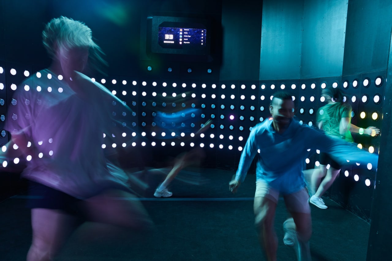 Players move quickly in front of an illuminated dot wall.