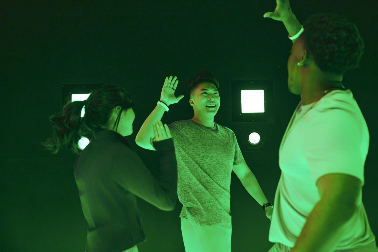 Players celebrate with high fives in a room lit green.