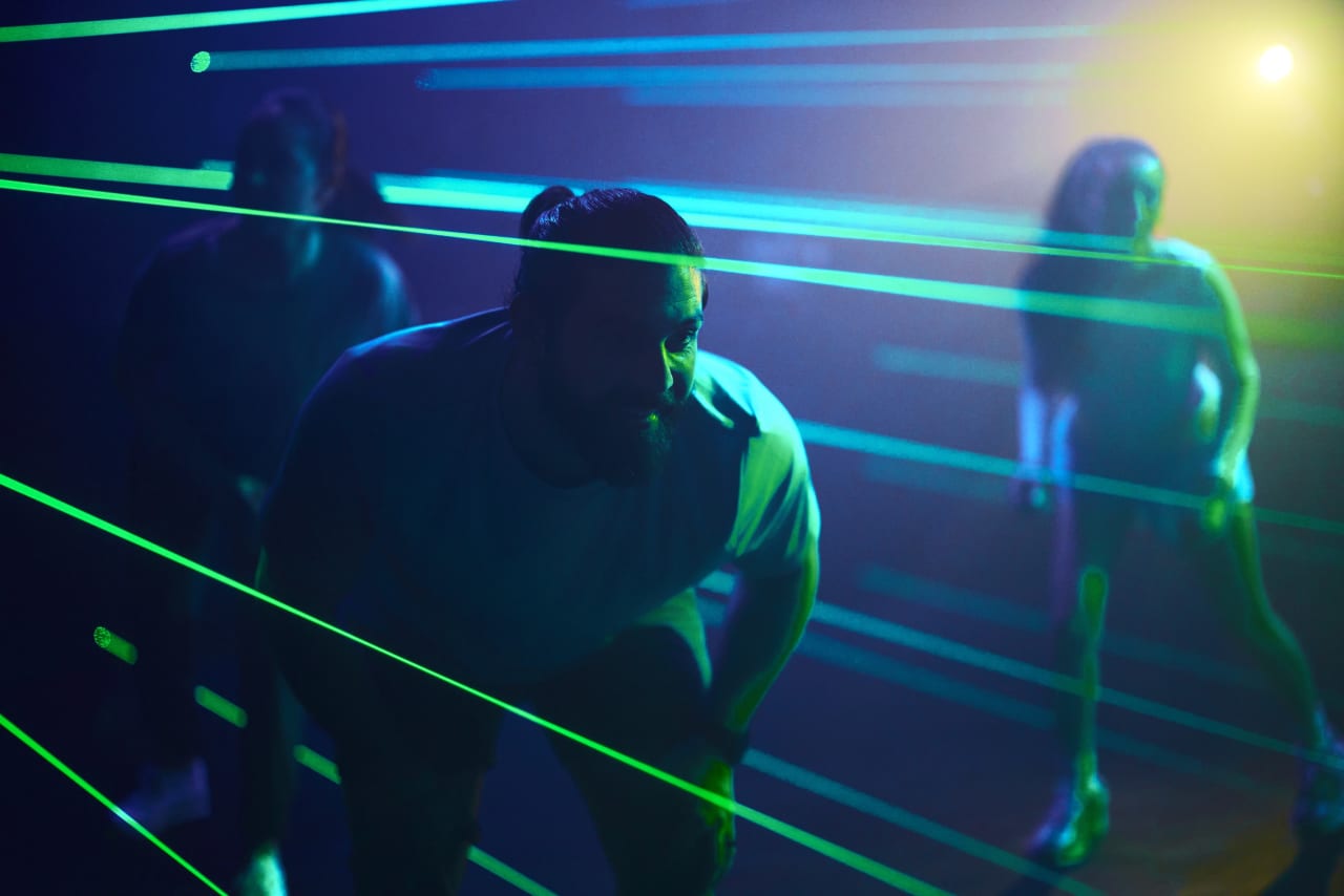 Players crouch through a dense field of green laser beams.