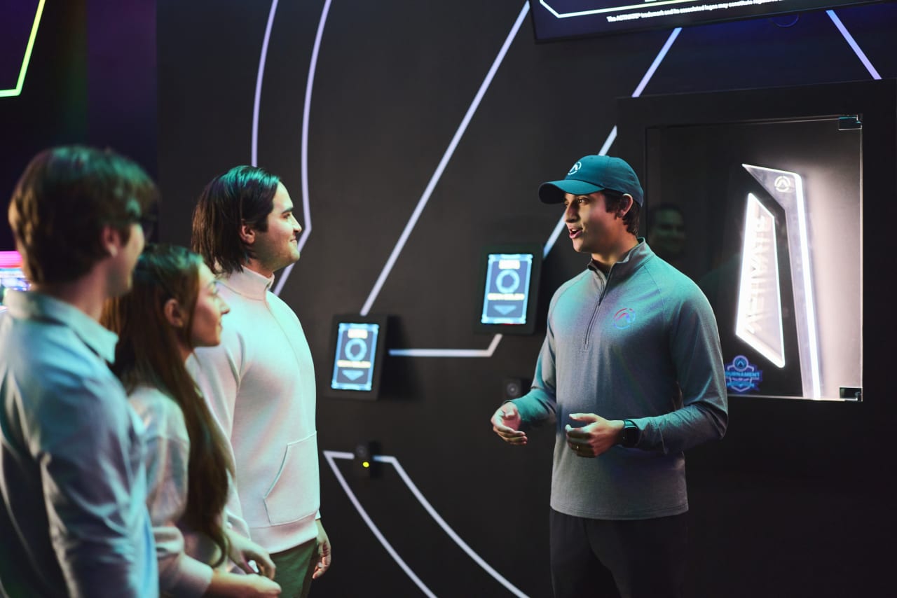 An Activate staff member helps a group check in at the kiosks.