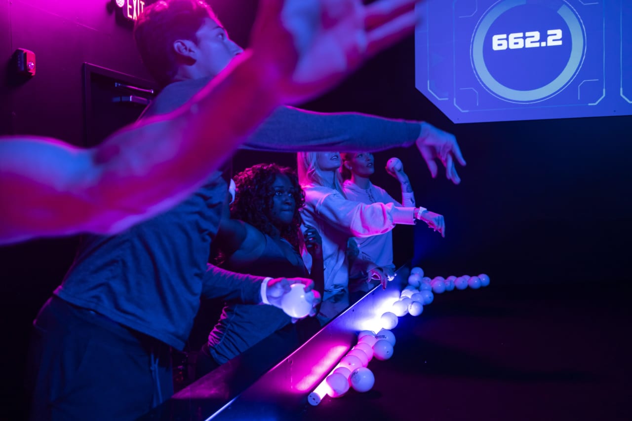 Players push glowing balls along a lit rail as their score climbs.