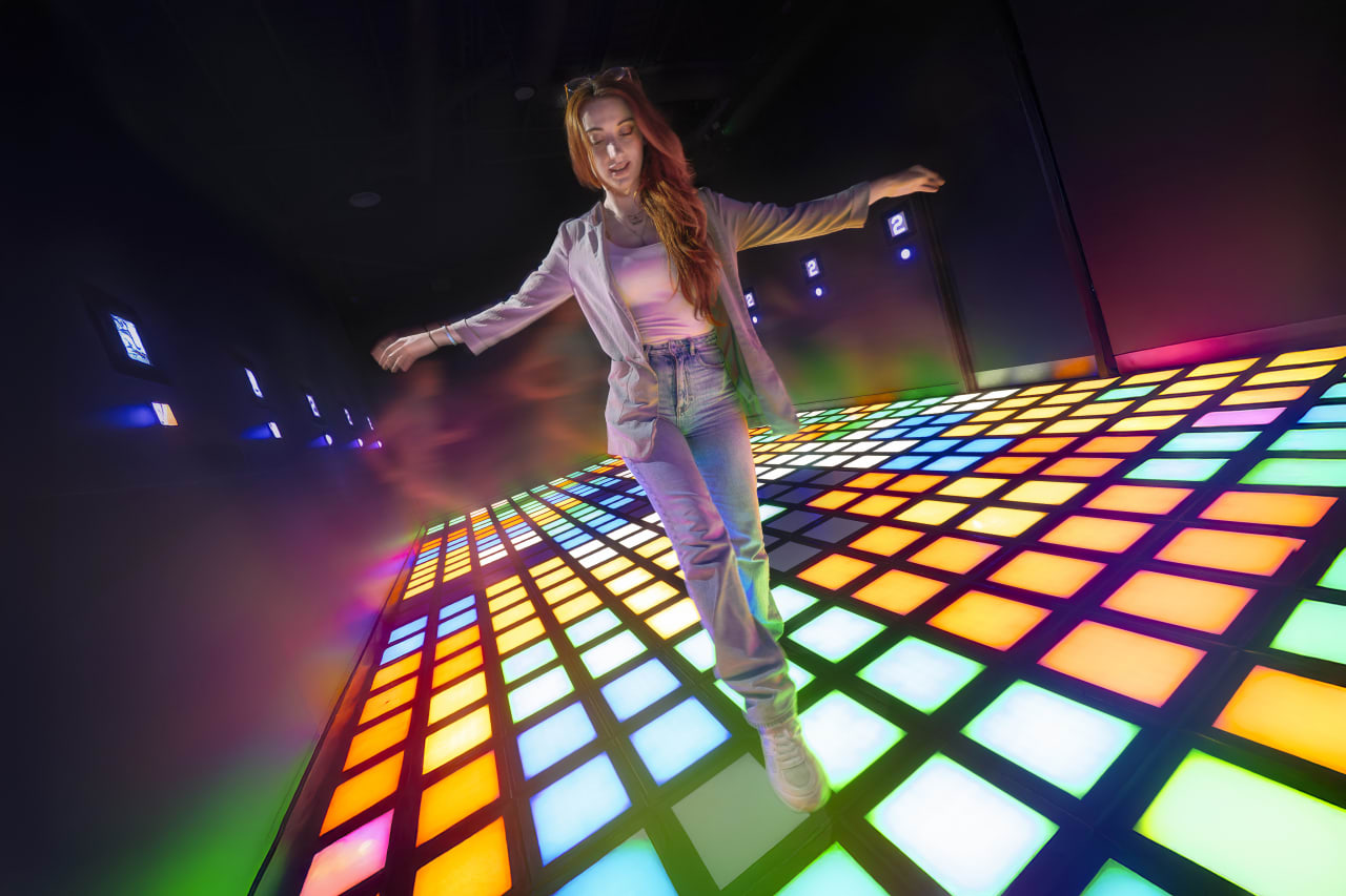 A player balances on a brightly lit floor grid.