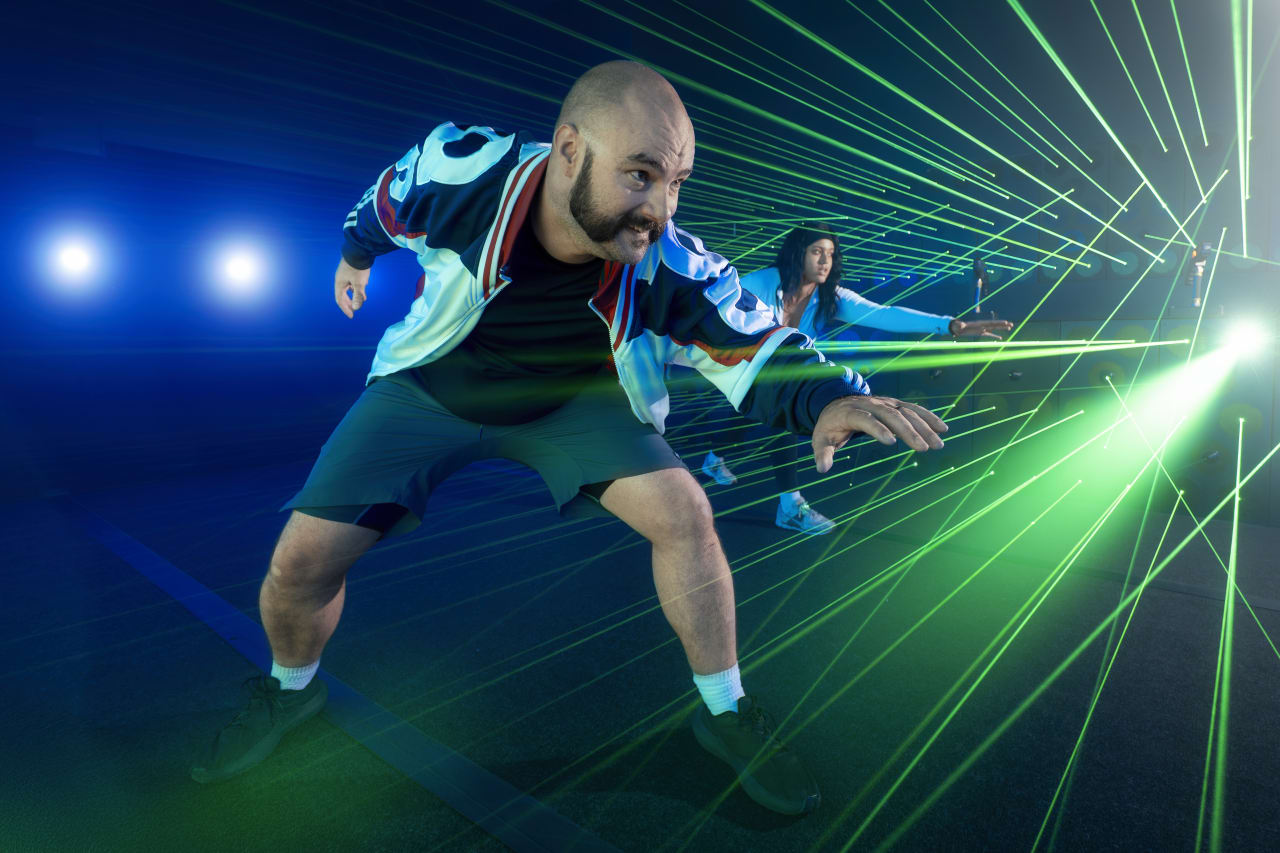 A player leans through a fan of green laser beams.