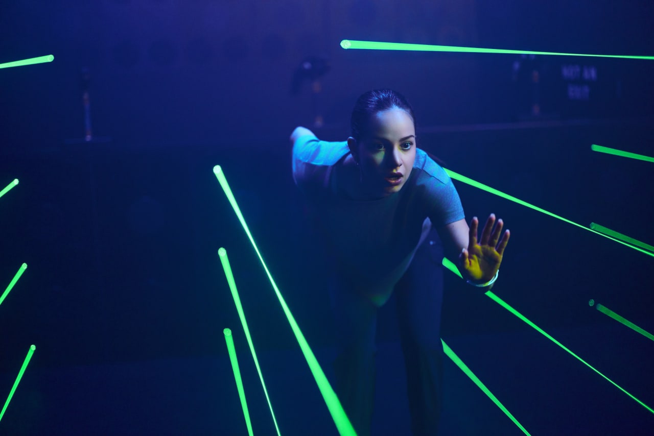 A player stretches between green laser beams in the Mega Laser room.