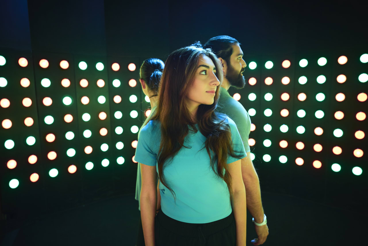 Two players look up at a wall of glowing coloured lights.