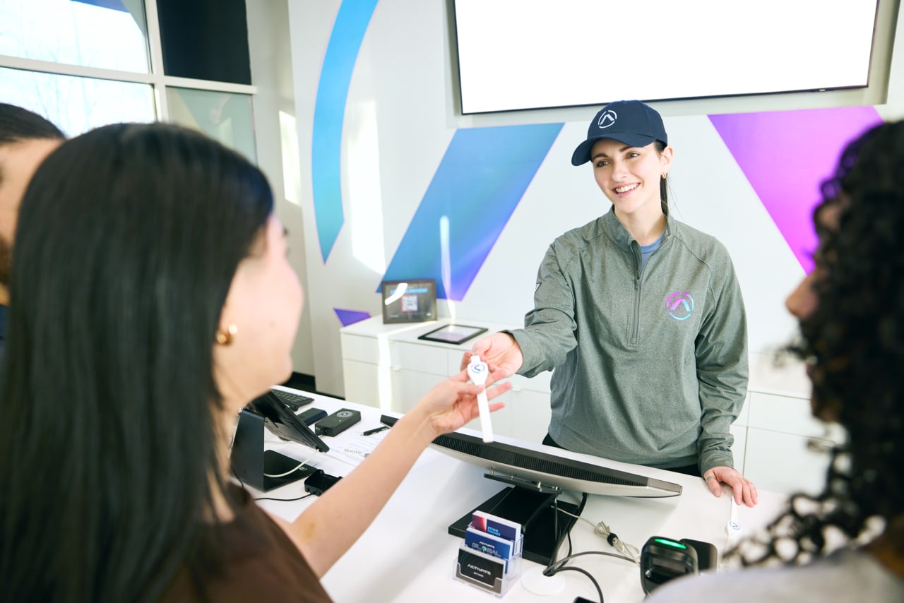 An Activate staff member hands a wristband to a guest at the lobby desk.