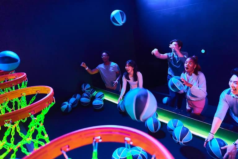 Players shooting balls into glowing basketball hoops