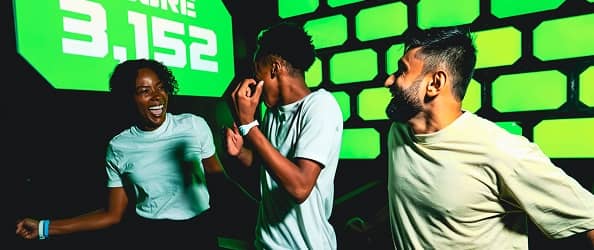 Friends celebrating a high score in a neon-lit Activate room.