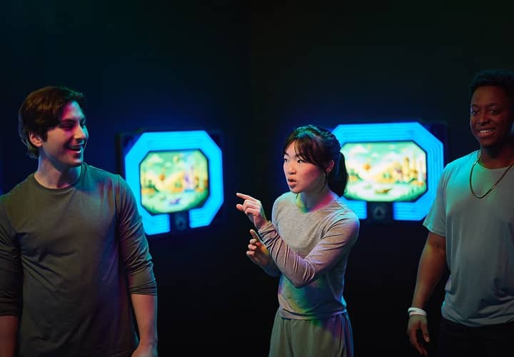 Friends laughing together in front of glowing game screens.