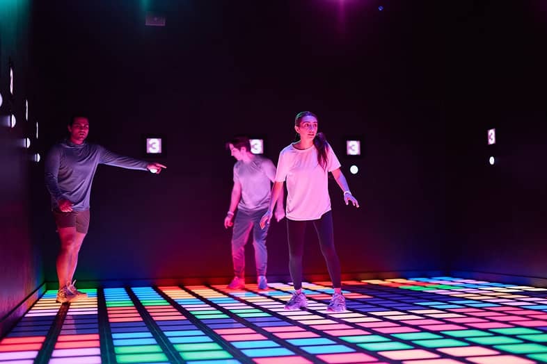 Players competing on a glowing light-up game floor
