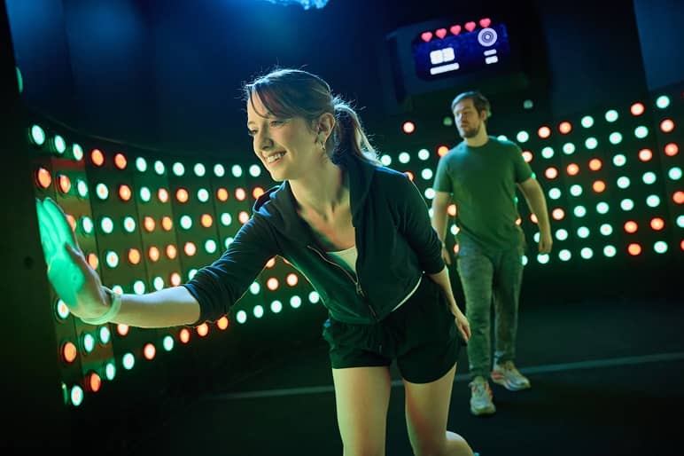 A player tapping glowing dots on an interactive light-up wall