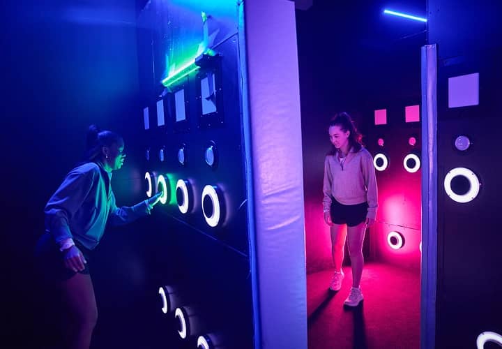 Players tapping glowing buttons on an interactive light-up wall.