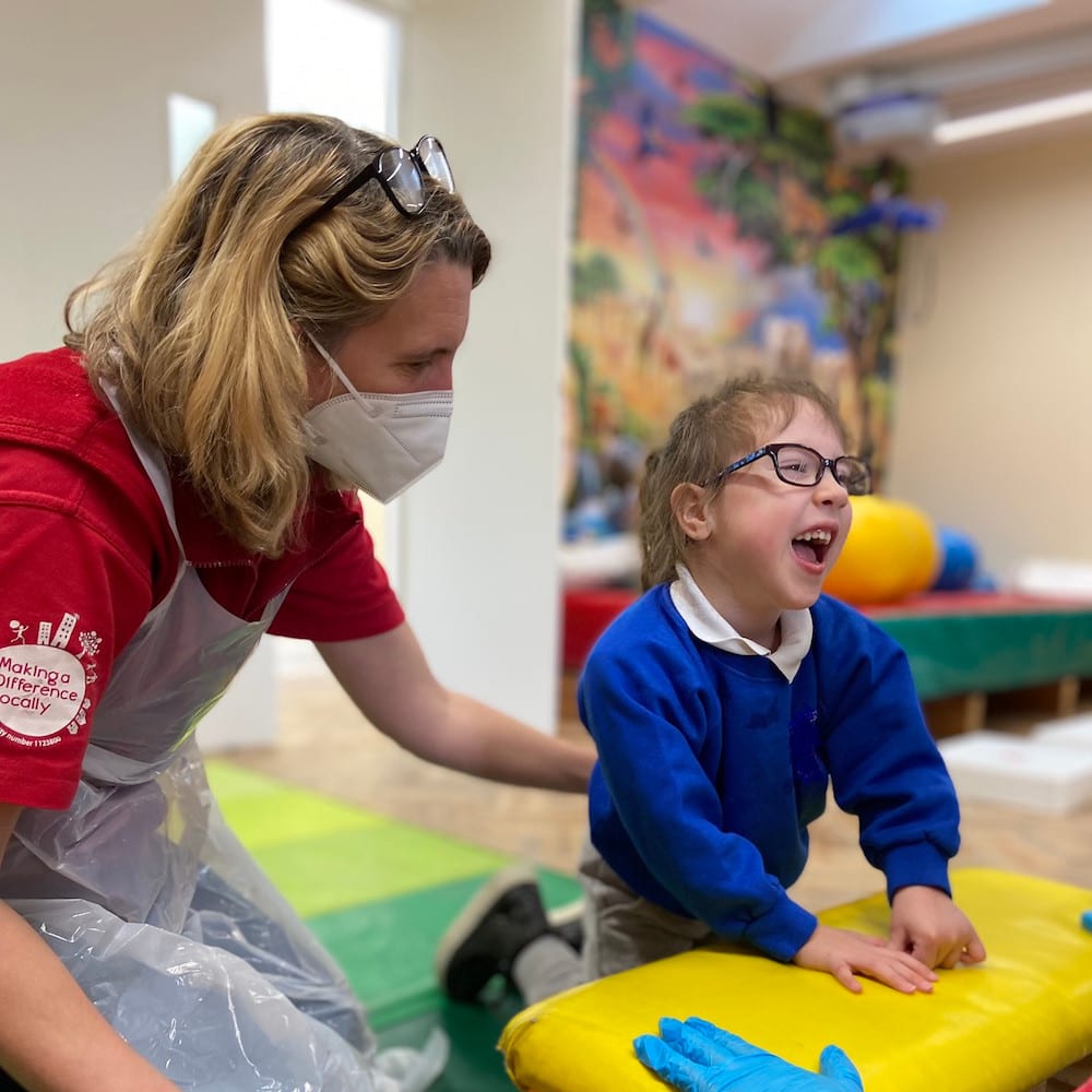 Andrea at work at Playskill, with a small child who is smiling