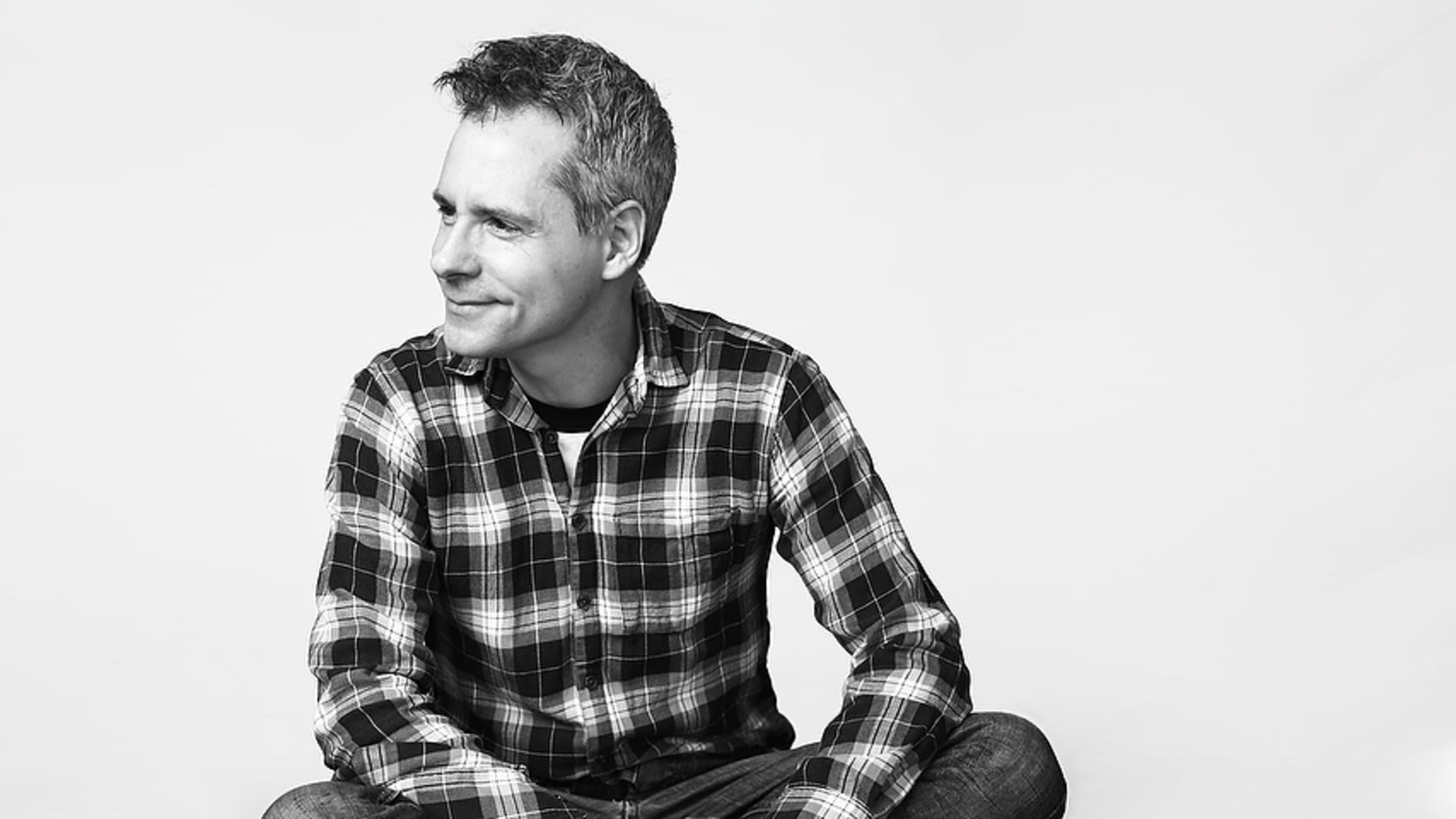 Portrait of playwright Bruce Norris, a white male, wearing a plaid collared shirt.
