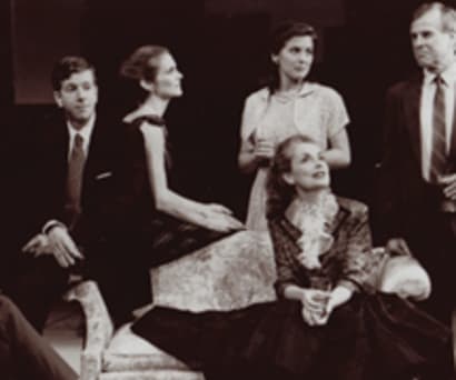 Actors Jack Gilpin, Robert Stanton, Julie Hagerty, Jennifer Van Dyck, Mary Beth Peil, and John Cunningham in A Cheever Evening. They sit and stand in a formal living room wearing suits and formal dresses.