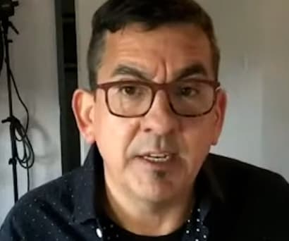 Artist Ken Gonzales-Day, a Mexican-American male wearing a black collared shirt and glasses, speaks at a virtual event.