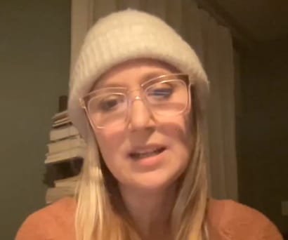 Playwright and actress Heather Raffo, an Iraqi-American woman wearing a peach sherling sweater, tan beanie hat, and glasses, leads a virtual Master Class.