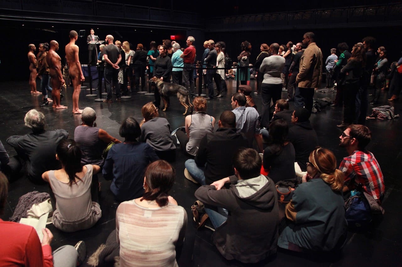 Black and white cut outs of two women stand at opposite ends of a yellow 'Please stand this far apart' sign inside Montrose subway station