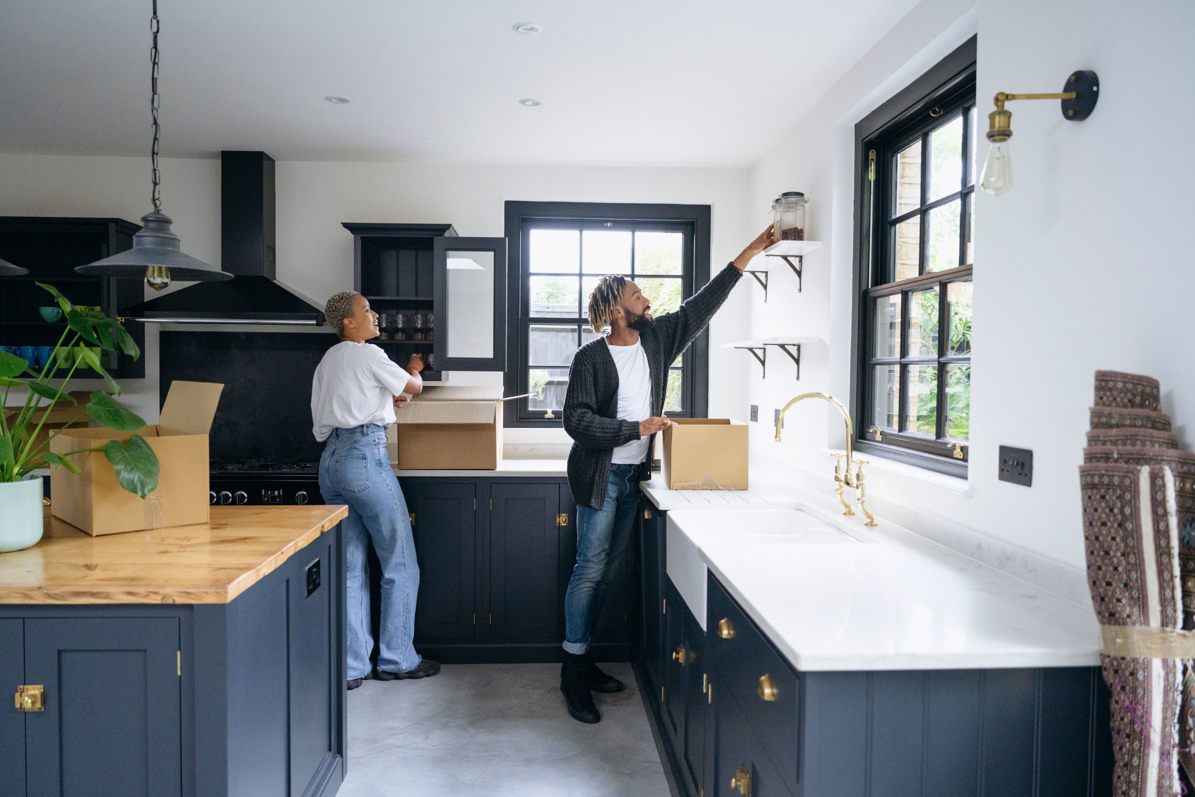 A young couple is unpacking boxes in brand new kitchen