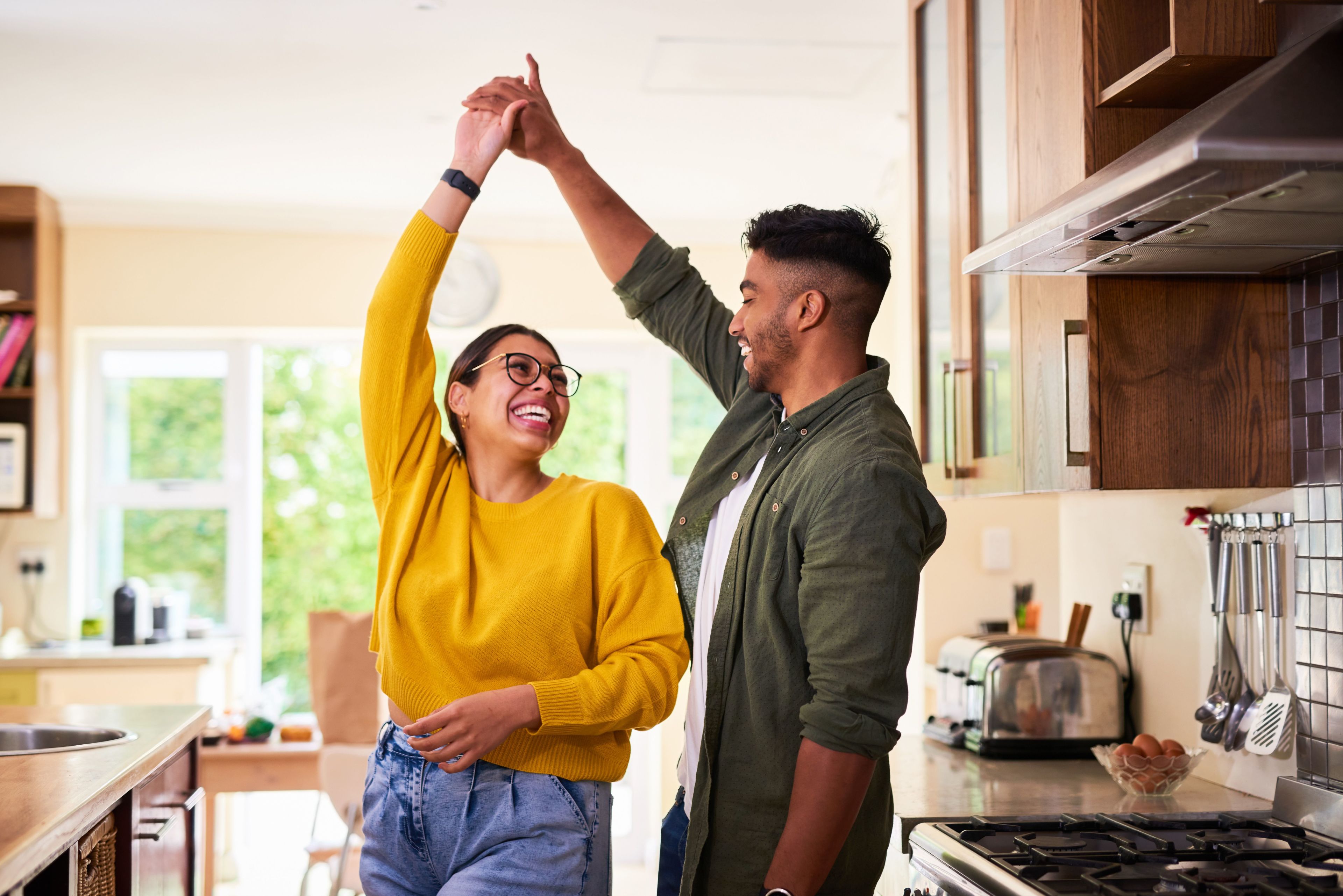 happy couple dancing and smiling in the kitchen together