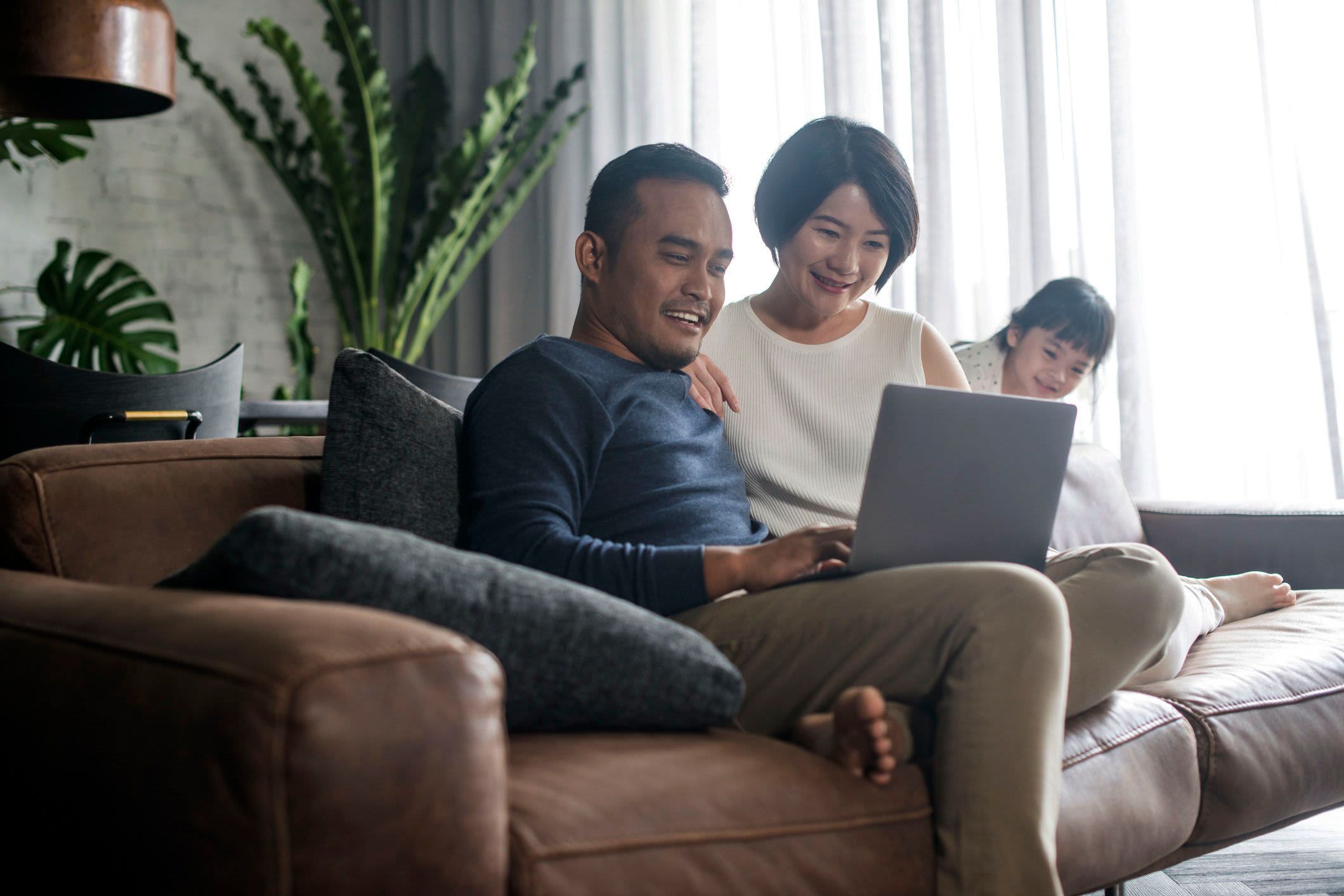 Couple Investing from couch with young daughter playing nearby