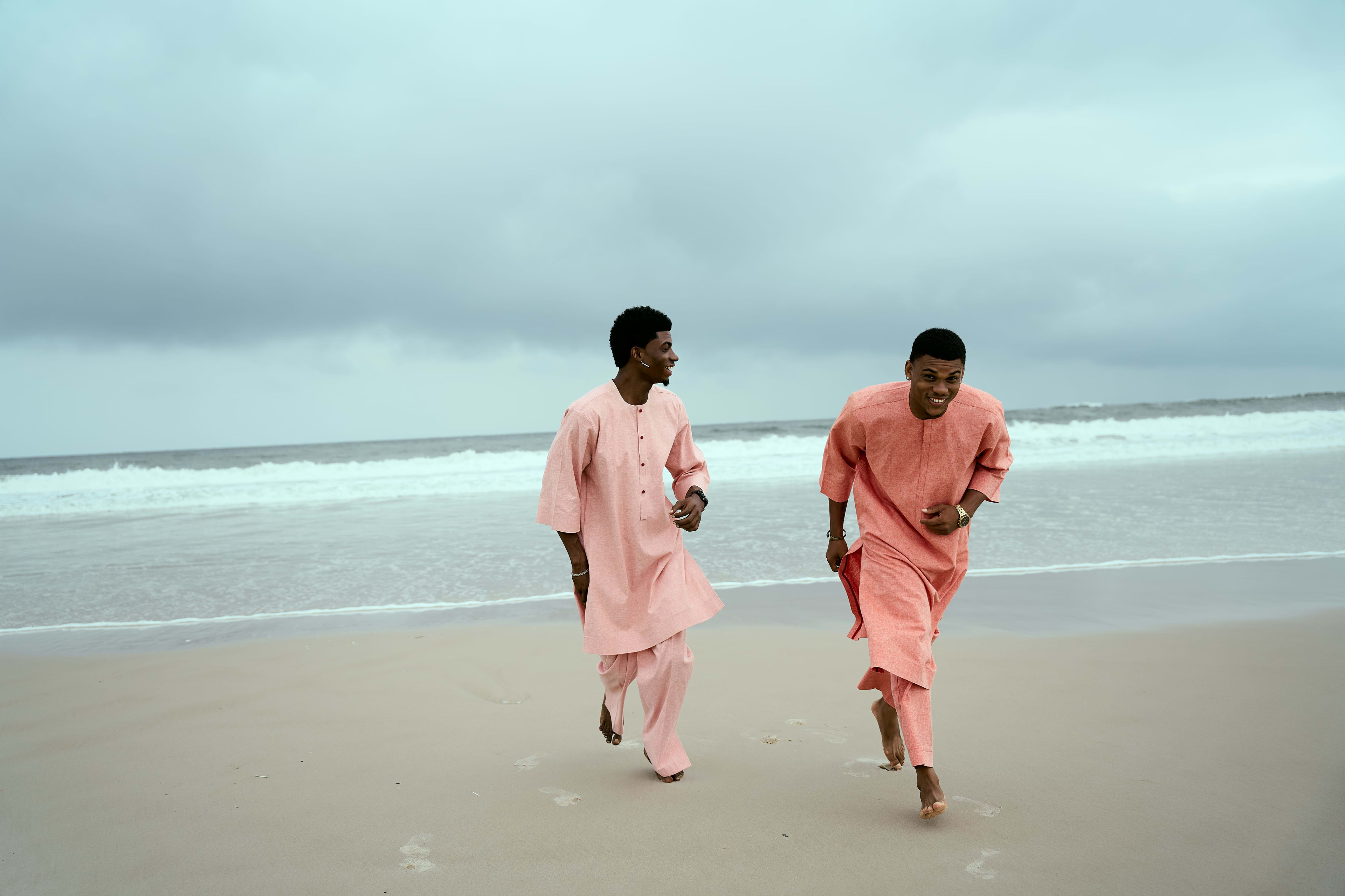 Two OnPoint models in matching coral two-piece sets, walking together on the beach