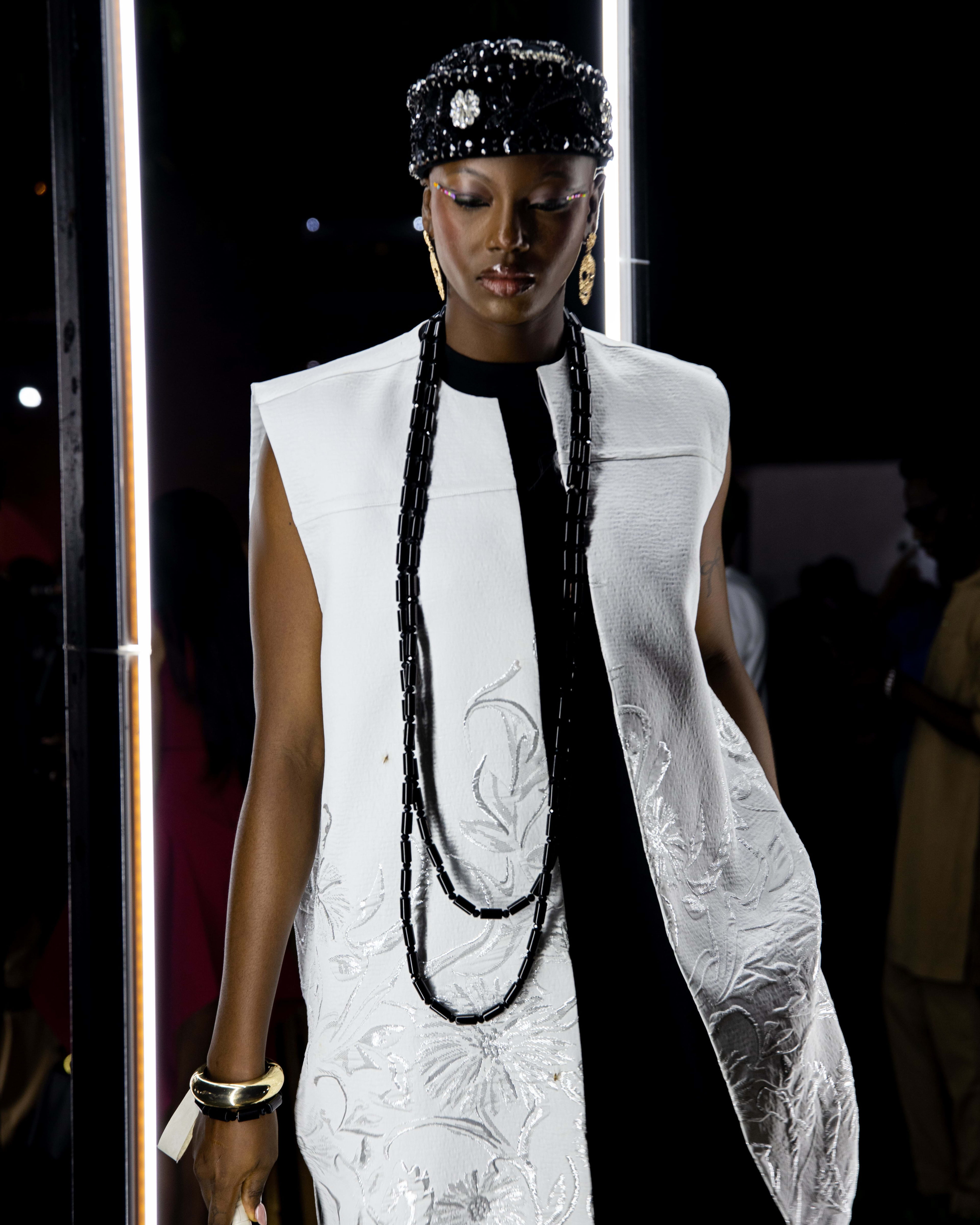 A model in a fur-trimmed ivory jacquard vest and beaded cap, close portrait